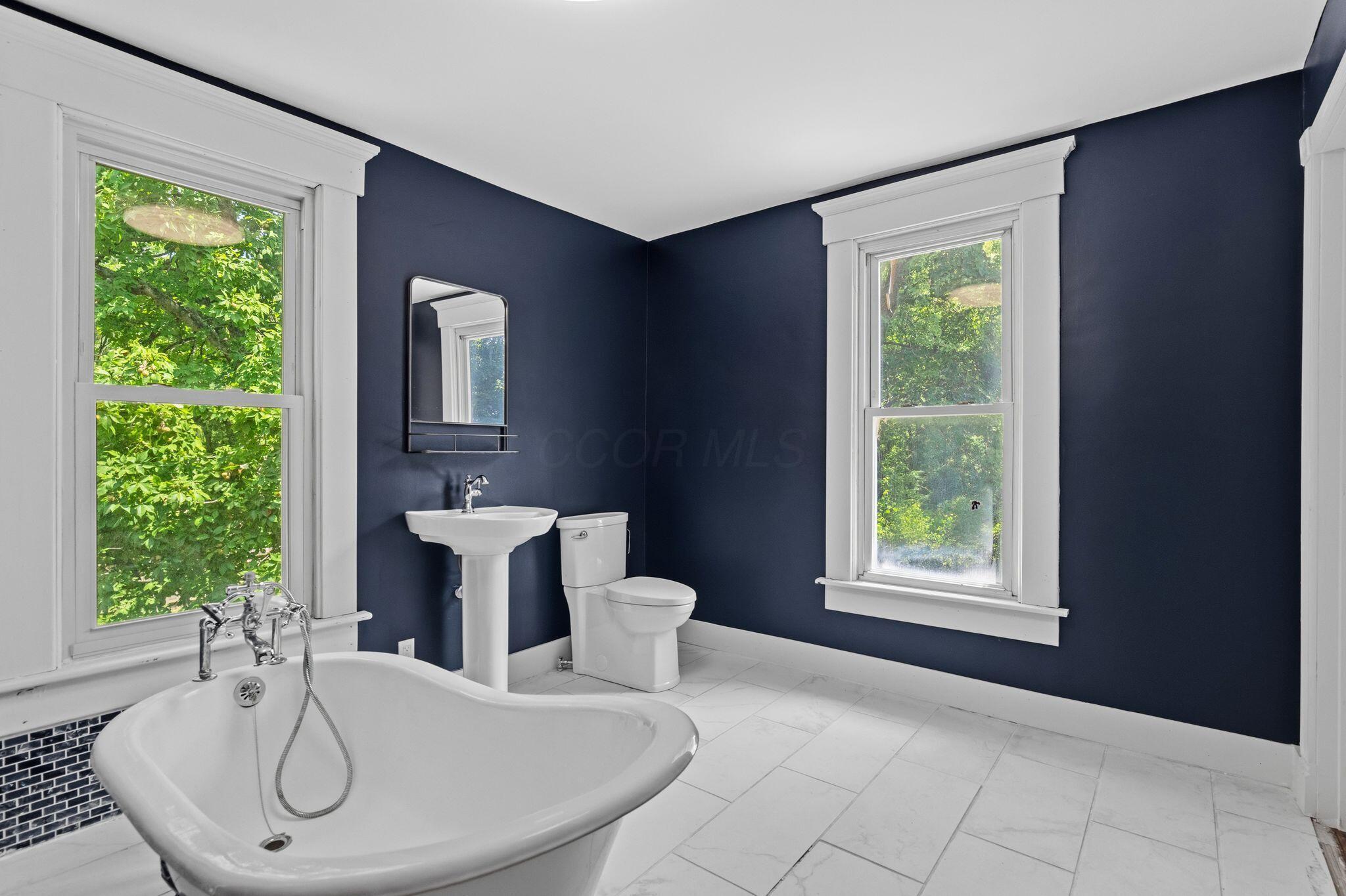 107 Price Road Columbus, OH 43230 - Photo 24 of 51 Bathroom featuring a freestanding tub with chrome fixtures, a pedestal sink, and a toilet