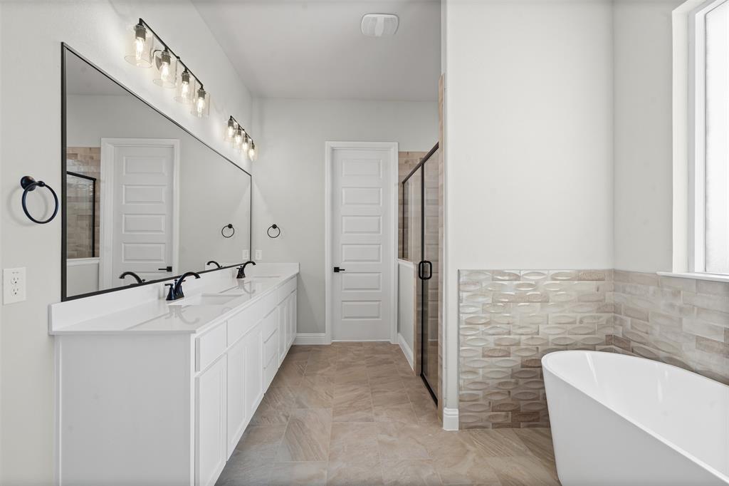 1005 Lilly Lane Weatherford, TX 76088 - Photo 23 of 34 a bathroom with a double vanity sink a mirror and a bathtub