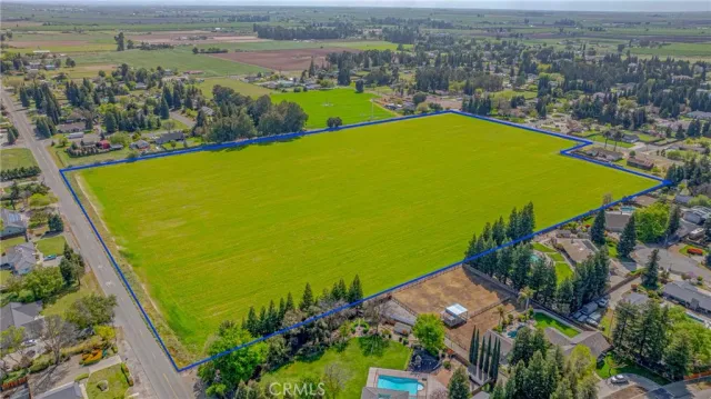 an aerial view of a residential houses with outdoor space and trees