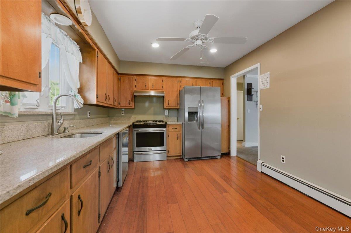 401 West Walnut Street, Unit UPPR Long Beach, NY 11561 - Photo 6 of 17 a kitchen with stainless steel appliances wooden floor sink and wooden cabinets