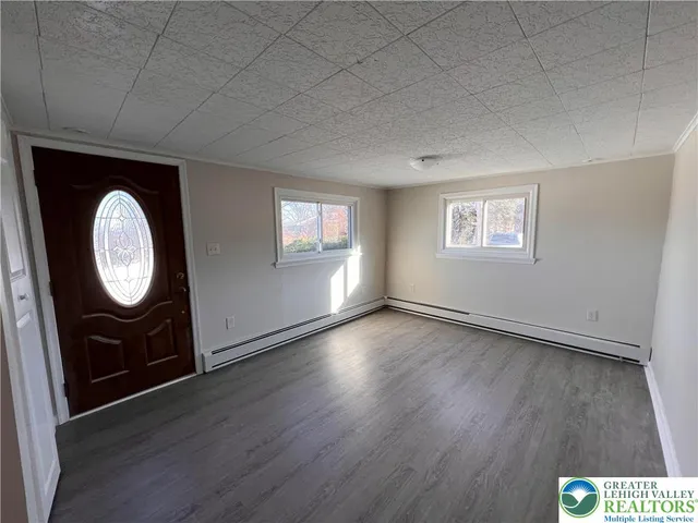an empty room with wooden floor mirror and windows