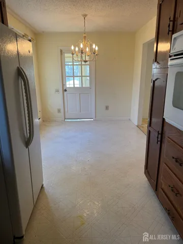 a view of empty room with floor to ceiling window and chandelier