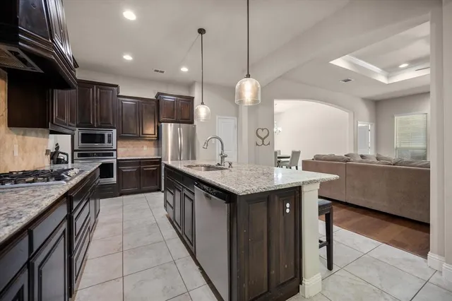 a kitchen with stainless steel appliances granite countertop a sink a stove and a wooden floors