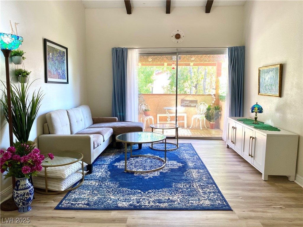 Living room with beamed ceiling and light wood-style flooring