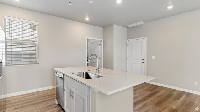 82 Provo River Road, Unit 251 Saratoga Springs, UT 84045 - Photo 11 of 32 Central kitchen island featuring a stainless steel sink with a high-arch faucet, light-toned countertop, and light gray cabinetry