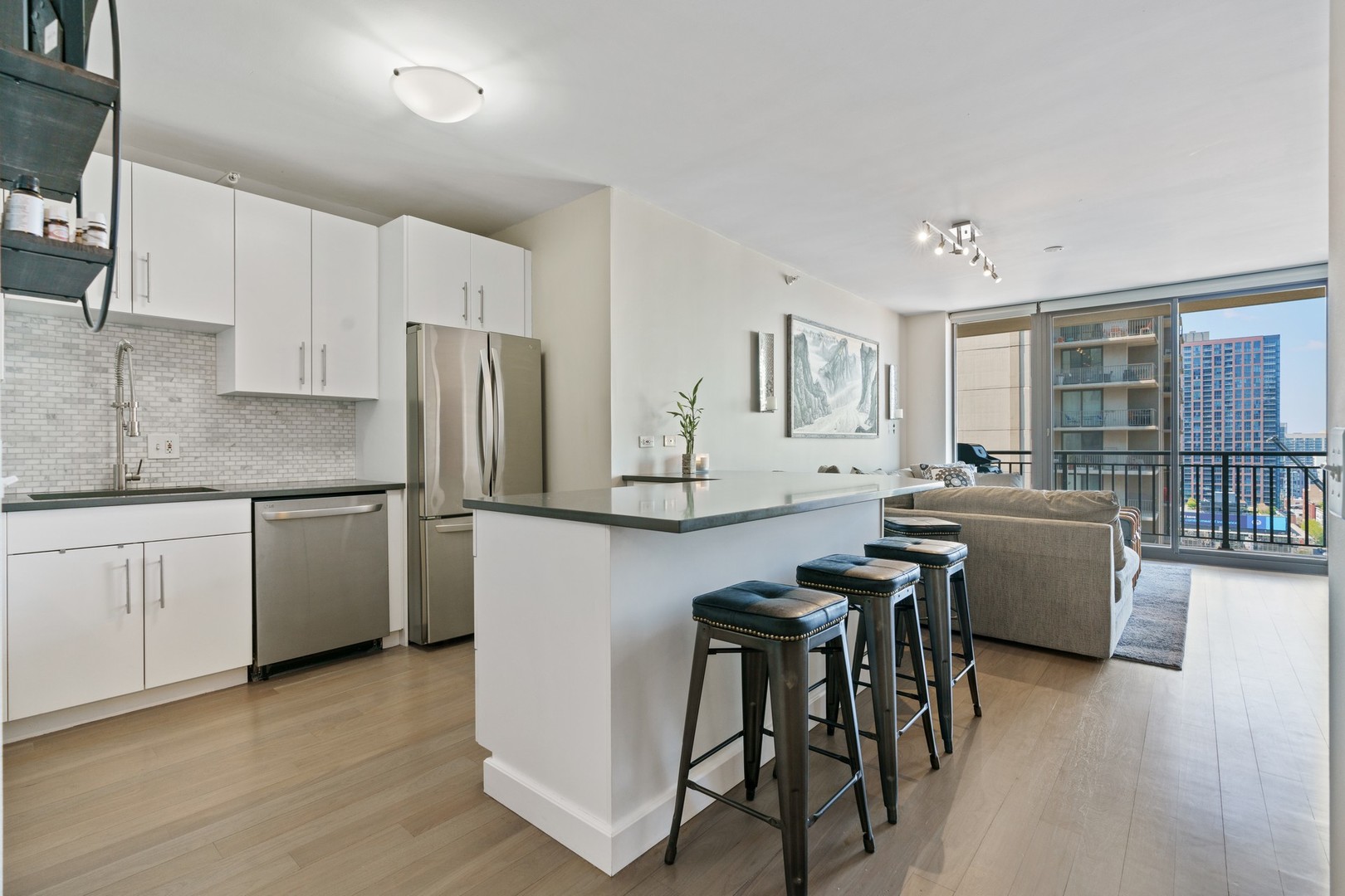 630 North State Street, Unit 2210 Chicago, IL 60654 - Photo 5 of 23 a kitchen with granite countertop a refrigerator a stove a sink and white cabinets with wooden floor