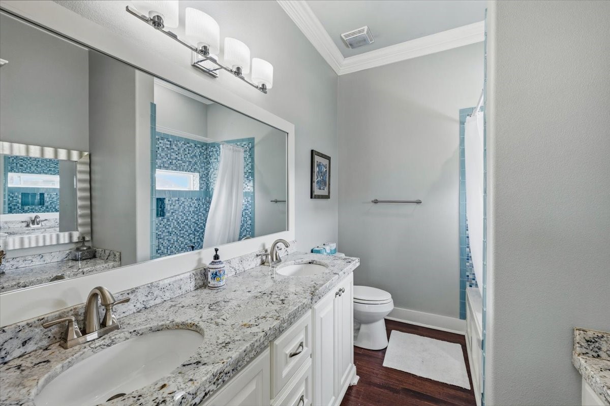 839 Eastview Crystal Beach, TX 77650 - Photo 29 of 44 a bathroom with a granite countertop sink a toilet and a mirror