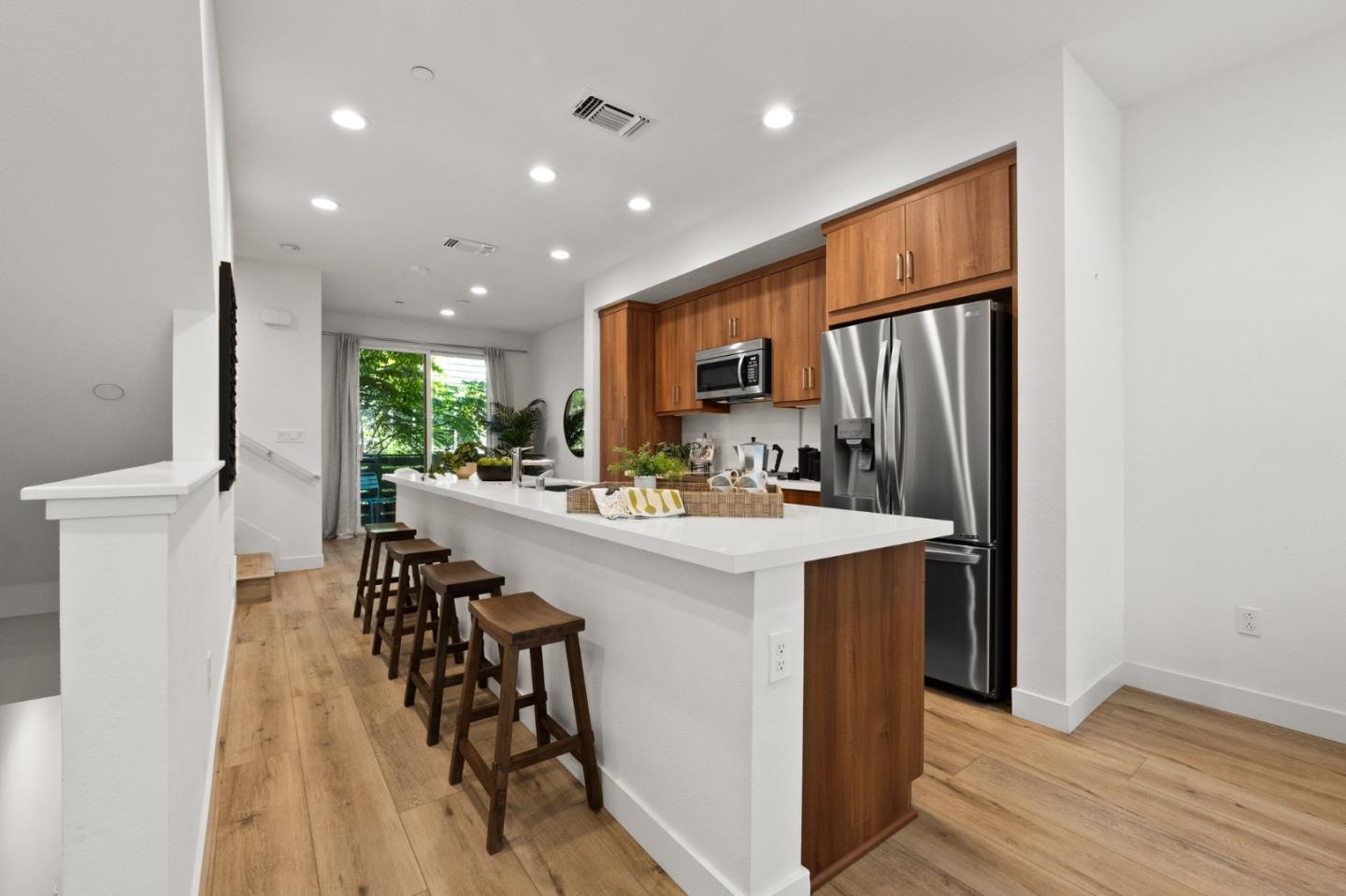 117 Uptown Circle Oakland, CA 94607 - Photo 7 of 25 a kitchen with stainless steel appliances a refrigerator a sink dishwasher a stove and a dining table with wooden floor
