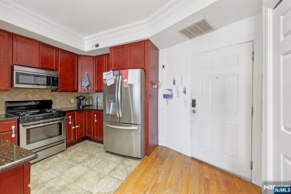 15 Tichenor Street, Unit 407 Newark, NJ 07102 - Photo 10 of 26 a kitchen with granite countertop a refrigerator and a stove top oven