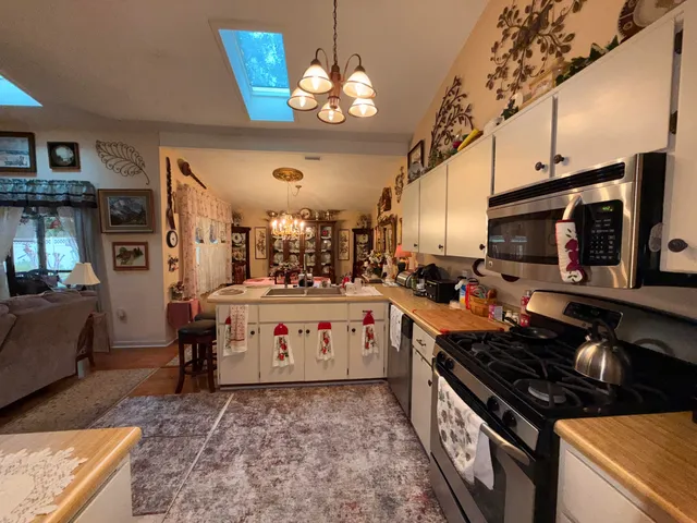 a large white kitchen with stainless steel appliances granite countertop a stove and a sink