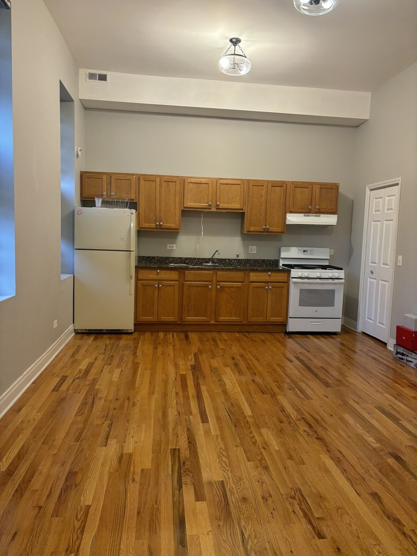 2002 West Chicago Avenue, Unit 2R Chicago, IL 60622 - Photo 5 of 17 a kitchen with granite countertop a stove and a refrigerator