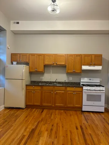 a kitchen with stainless steel appliances granite countertop a sink dishwasher stove top oven and cabinets with wooden floor