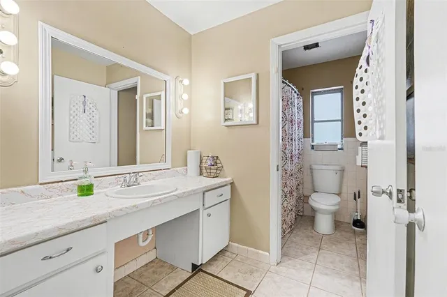 a bathroom with a granite countertop toilet sink and mirror