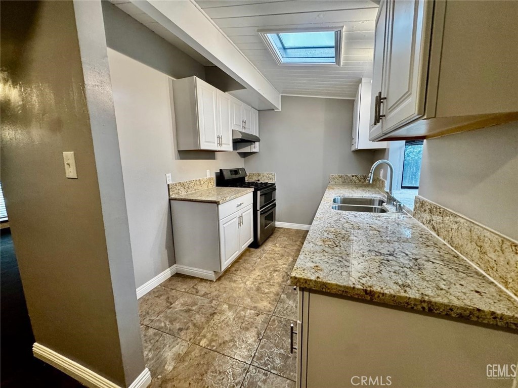 9 Dunlap Street Bakersfield, CA 93309 - Photo 14 of 22 a kitchen with granite countertop a sink a stove top oven and cabinetry