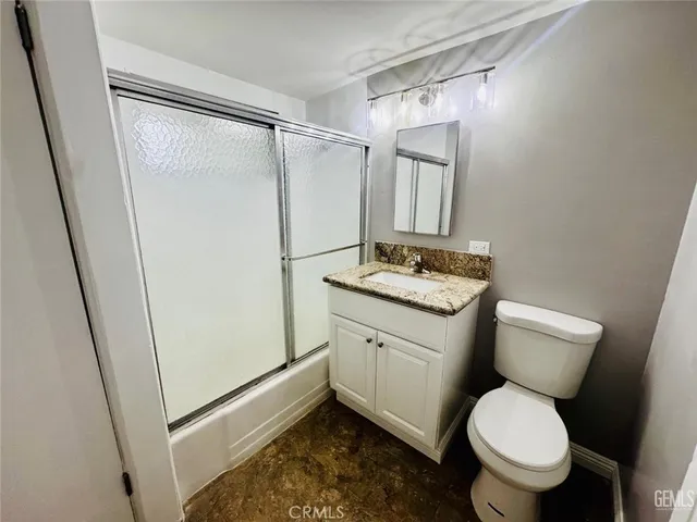 a bathroom with a granite countertop sink toilet and shower