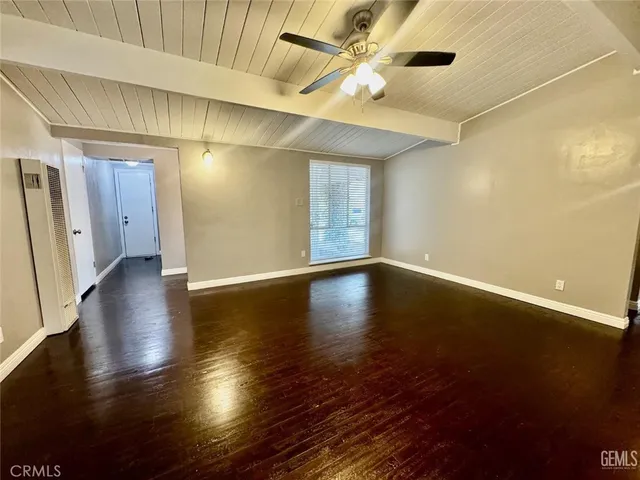an empty room with wooden floor and windows with curtains