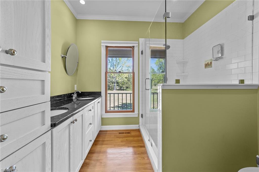 130 Deer Path Summerfield, NC 27358 - Photo 9 of 50 Primary bathroom with double sink and standalone shower with glass enclosure.