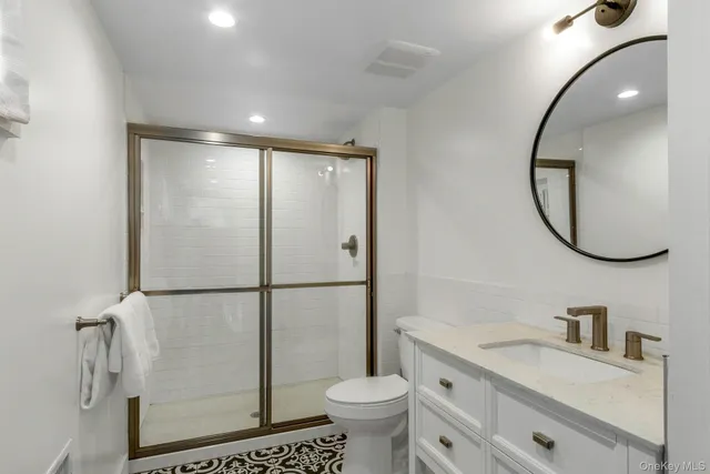 a bathroom with a granite countertop toilet sink and mirror