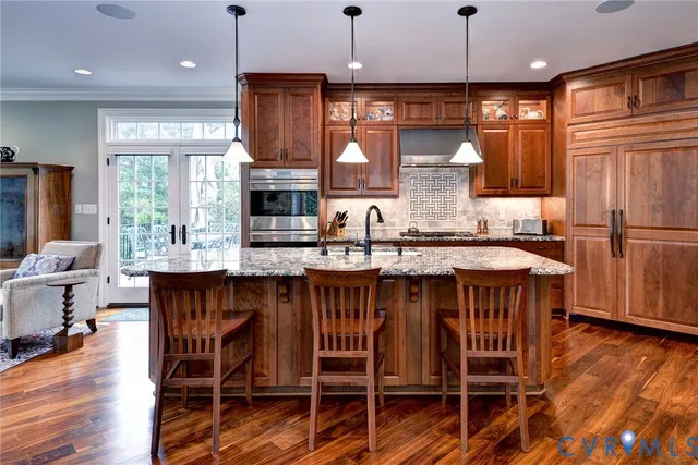 a kitchen with stainless steel appliances granite countertop a table chairs sink and wooden cabinets