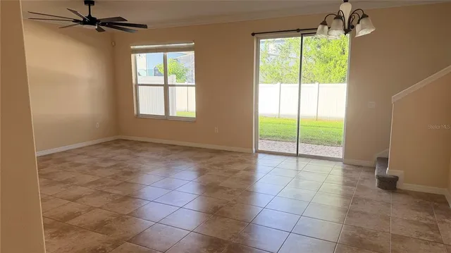 a view of an empty room and window chandelier fan
