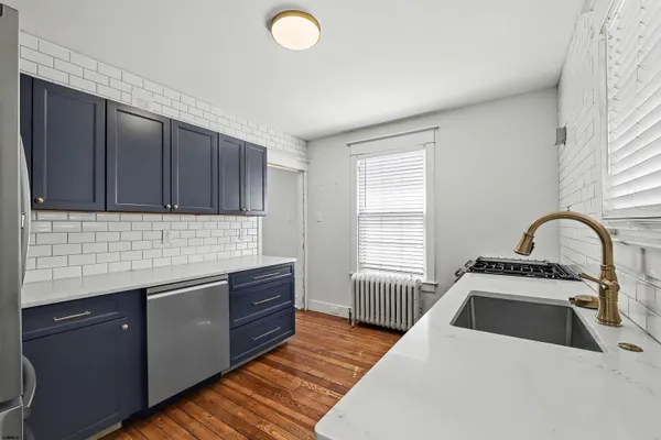 a kitchen with stainless steel appliances granite countertop a sink a stove and a wooden floors