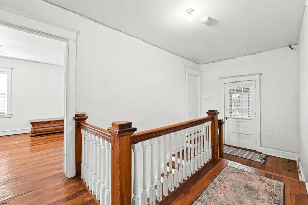 a view of a hallway with wooden floor and staircase
