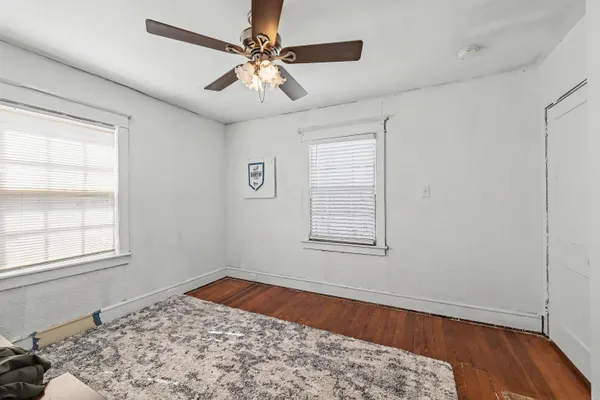 a view of a bedroom with wooden floor and window