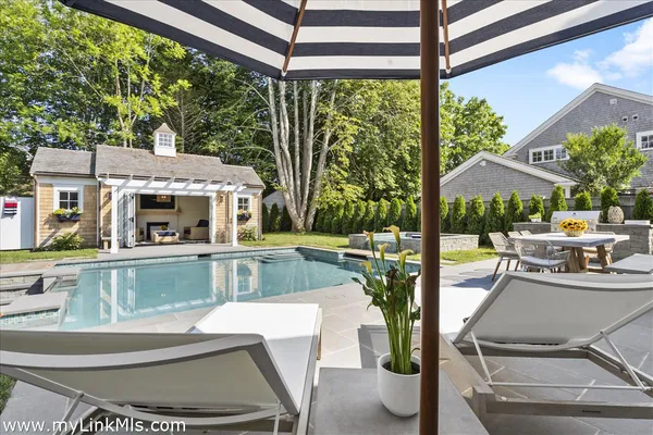 a view of a patio with couches table and chairs under an umbrella