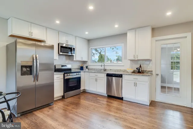 a kitchen with granite countertop a refrigerator and a stove top oven