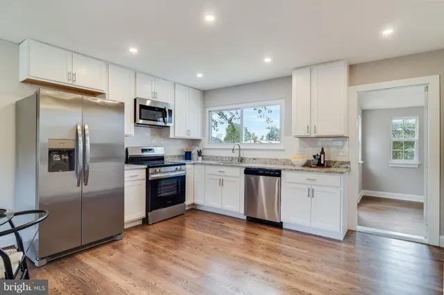 a kitchen with granite countertop a refrigerator and a stove top oven