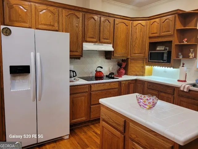 a kitchen with stainless steel appliances a refrigerator a sink a stove and white cabinets