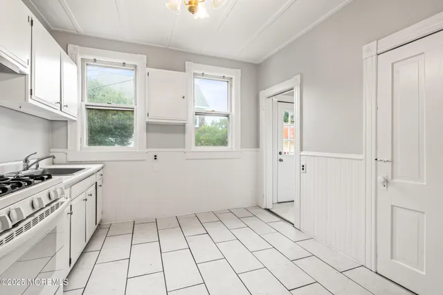 a view of a kitchen with white cabinets and window