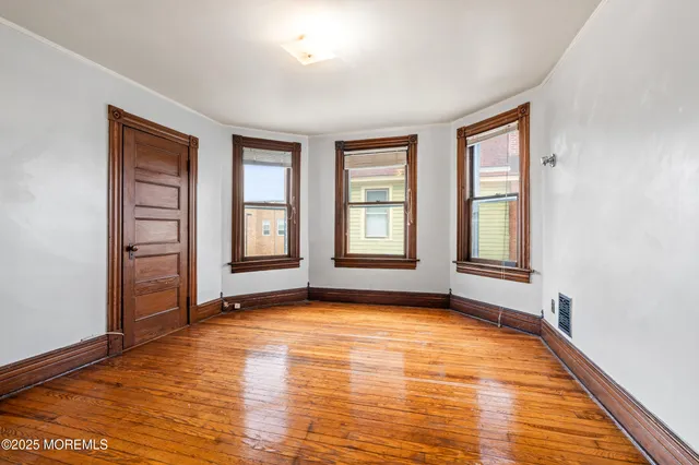 a view of an empty room with window and wooden floor