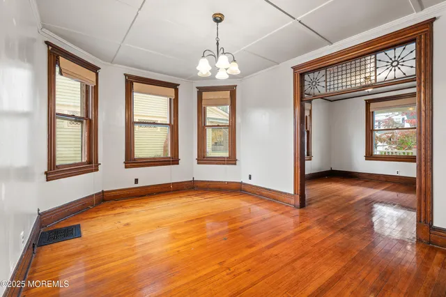 a view of an empty room with wooden floor and windows