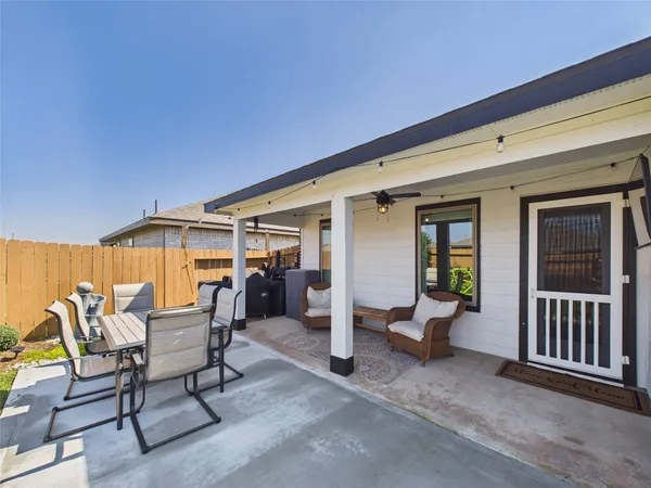a view of a patio with table and chairs near a barbeque