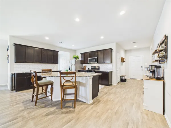 a view of a kitchen with kitchen island a counter top space a sink cabinets and stainless steel appliances