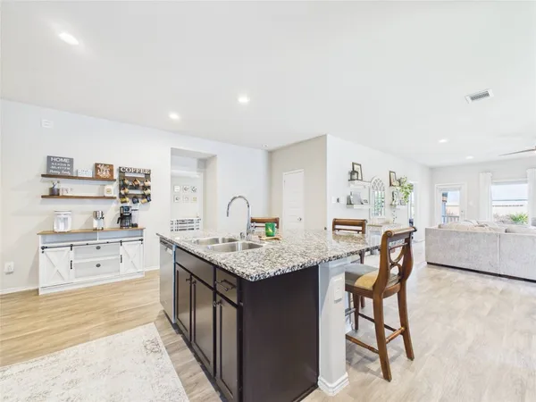 a kitchen with stainless steel appliances granite countertop a table chairs in it and wooden floors