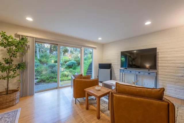 a living room with furniture a flat screen tv and a floor to ceiling window