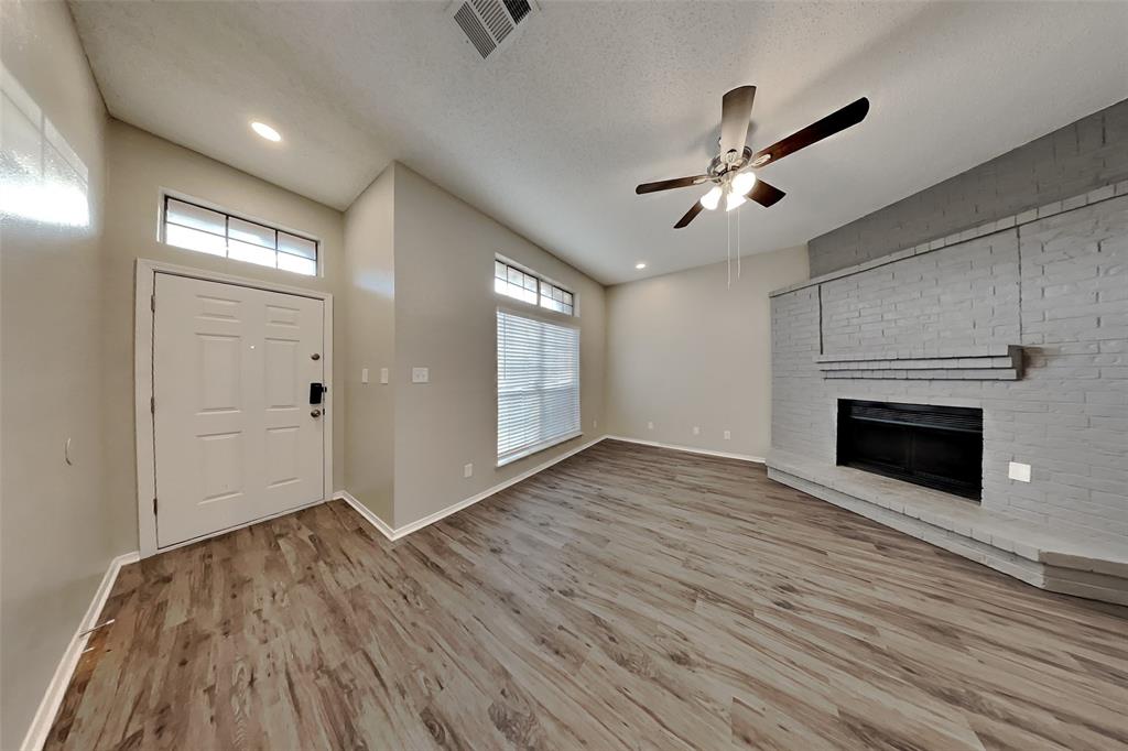 4013 David Circle Rowlett, TX 75088 - Photo 2 of 19 an empty room with wooden floor a ceiling fan a fireplace and windows