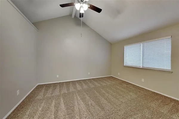 an empty room with a chandelier fan and windows