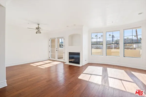 wooden floor in an empty room with a fireplace and a window