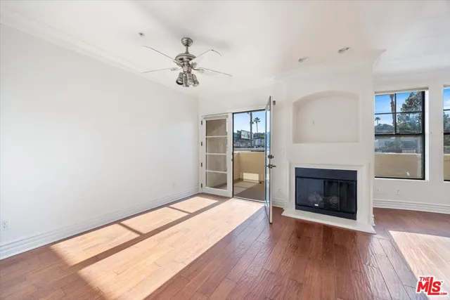 an empty room with wooden floor fireplace and windows
