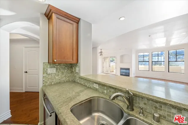 a view of a kitchen island with stainless steel appliances granite countertop a sink and a window