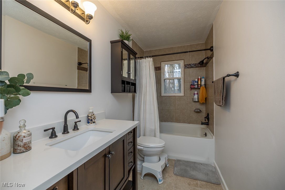 1060 Ledge Road Macedonia, OH 44056 - Photo 11 of 26 Full bathroom with a textured ceiling, toilet, tile patterned floors, vanity, and shower / tub combo with curtain