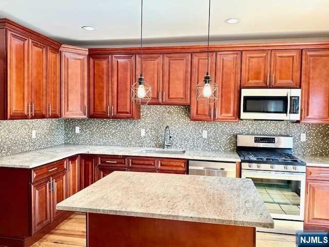 1249 Beaumont Avenue Teaneck, NJ 07666 - Photo 11 of 23 a kitchen with stainless steel appliances wooden cabinets a stove top oven a sink and dishwasher