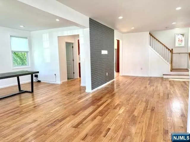 a view of a hallway with wooden floor and a bathroom