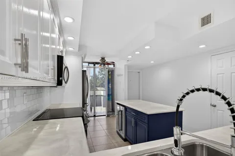 a kitchen with stainless steel appliances kitchen island granite countertop a refrigerator and a wooden floor