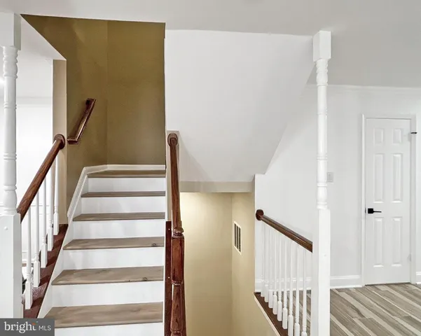 a view of staircase with wooden floor and white walls