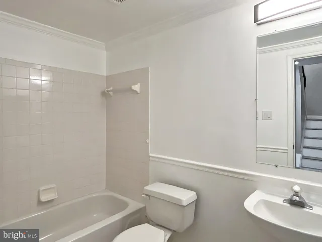 a bathroom with a granite countertop bathtub shower sink vanity and toilet