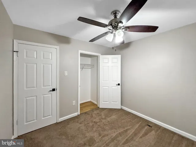 an empty room with closet and a chandelier fan